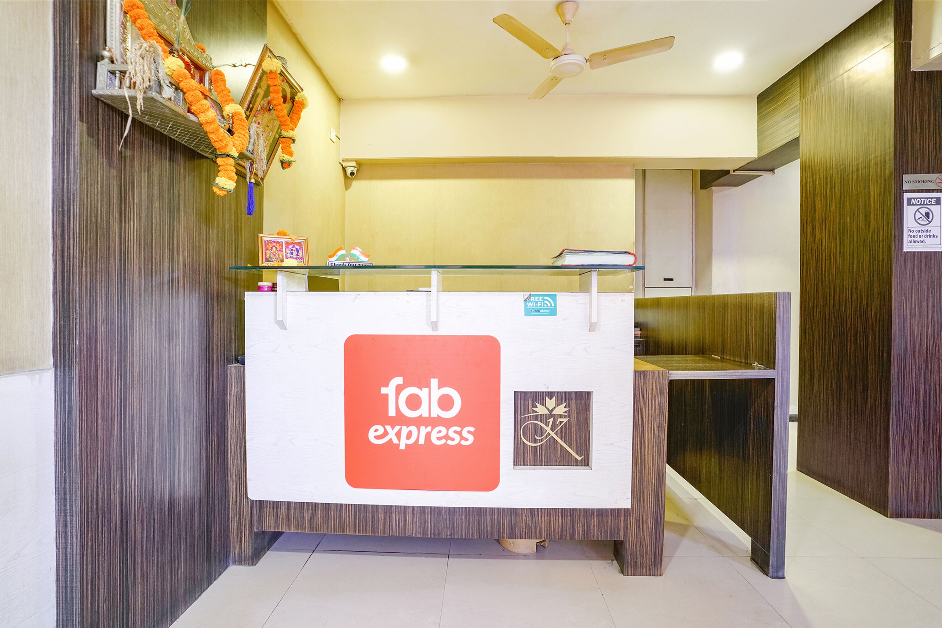 A reception desk with a 'fab express' logo, a ceiling fan, and a 'no smoking' sign.