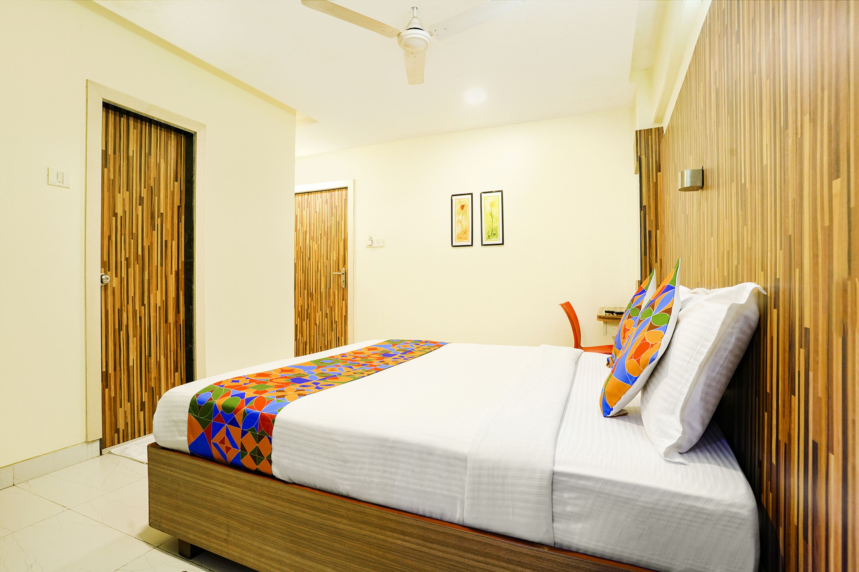 A neatly arranged bedroom with a bed, wooden wardrobe, and a ceiling fan.