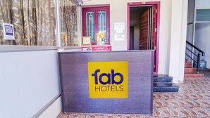 Uma receção com o letreiro 'fab hotels', uma porta vermelha e uma escadaria a subir para um andar superior.