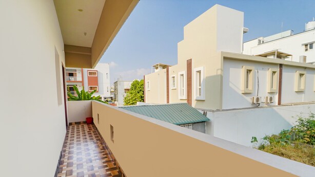 Um edifício residencial com varanda coberta por telhas, telhado verde e casas vizinhas.
