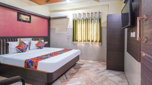 A hotel room with a bed, a ceiling fan, an air conditioning unit, a television, and a window with curtains. - Fabhotel Sai National (Visakhapatnam)