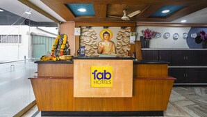 A reception desk with a Buddha statue, a clock, and a calendar on the wall. - Fabhotel Sai National (Visakhapatnam)