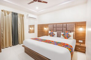 Una habitación de hotel moderna con una cama grande, cabecera de madera y un ventilador de techo.