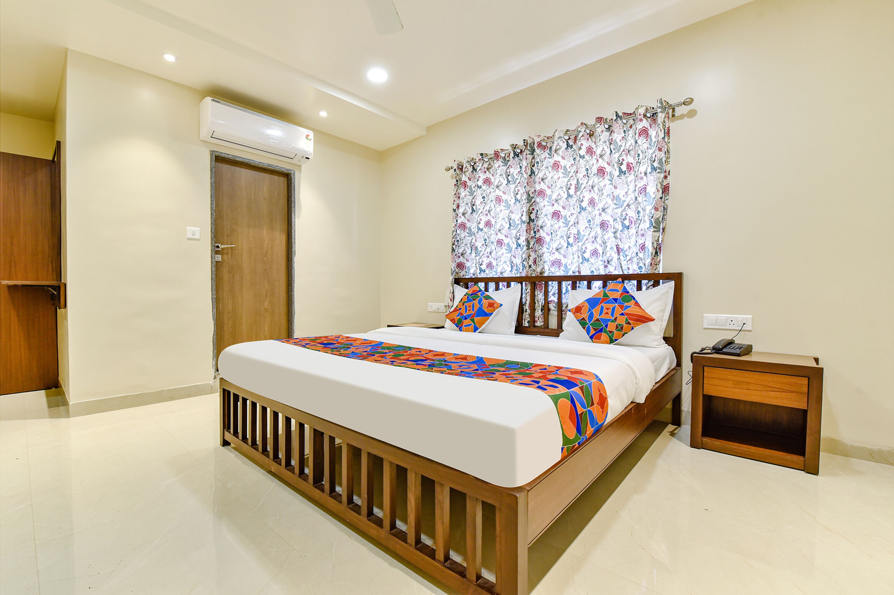 A bedroom with a wooden bed, a nightstand, an air conditioning unit, and a door.