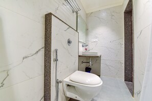 Et badeværelse med toilet, bruser og vask.