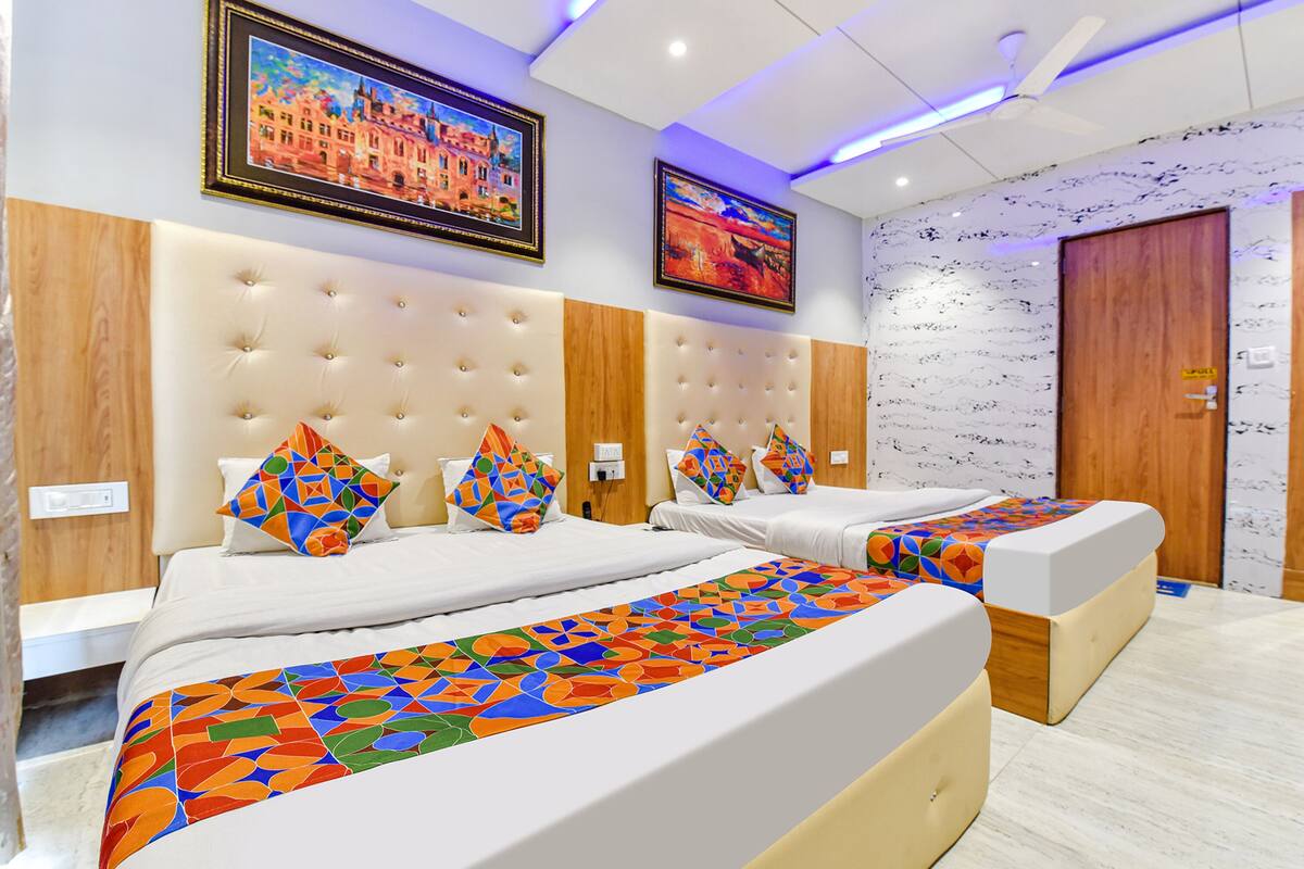 Una habitación de hotel con dos camas, un cabecero grande y acolchado, y una colcha con un estampado geométrico colorido.