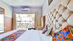 Habitación de hotel con una cama grande, vistas al exterior y un balcón con mesa y sillas.