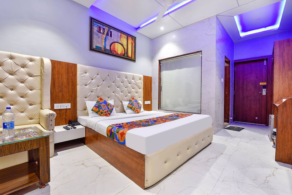 Una habitación de hotel moderna con una cama grande, una mesita de noche, un armario y la puerta del baño.