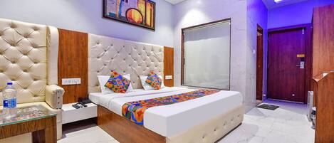 A modern hotel room with a large bed, a bedside table, a wardrobe, and a bathroom door.