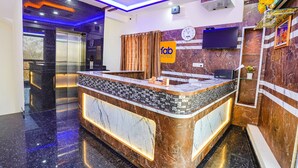 A hotel reception area with a marble counter, a clock, and a TV on the wall. - Fabhotel Sri Ram Comforts (Bengaluru)