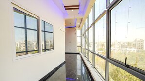 A corridor with large windows, a polished floor, and a ceiling with recessed lighting. - Fabhotel Sri Ram Comforts (Bengaluru)