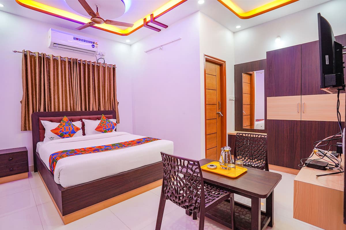 A hotel room with a bed, a desk, a chair, a TV, and a wardrobe.