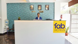 En reception med receptionist, blå væg med mønster, og et skilt med 'fab hotels'.