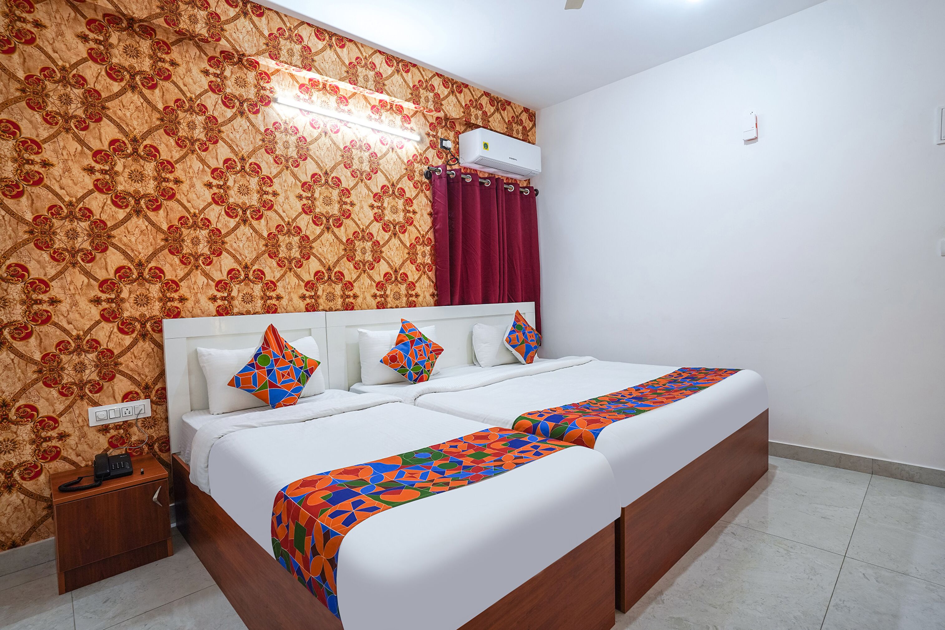 A hotel room with a large bed, patterned wallpaper, and a red curtain.