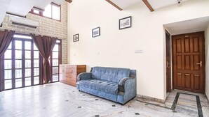A spacious room with a blue sofa, a wooden cabinet, and a door. - Fabexpress Duplex Villa (Barasat)