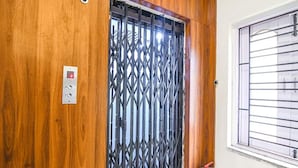 A wooden door with a metal security gate, a control panel, and a window with blinds. - Fabexpress Duplex Villa (Barasat)