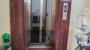 Een lift met een digitaal display, een waterfontein en een potplant.