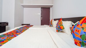 Een hotelkamer met een bed, kussens, een bureau en een deur.