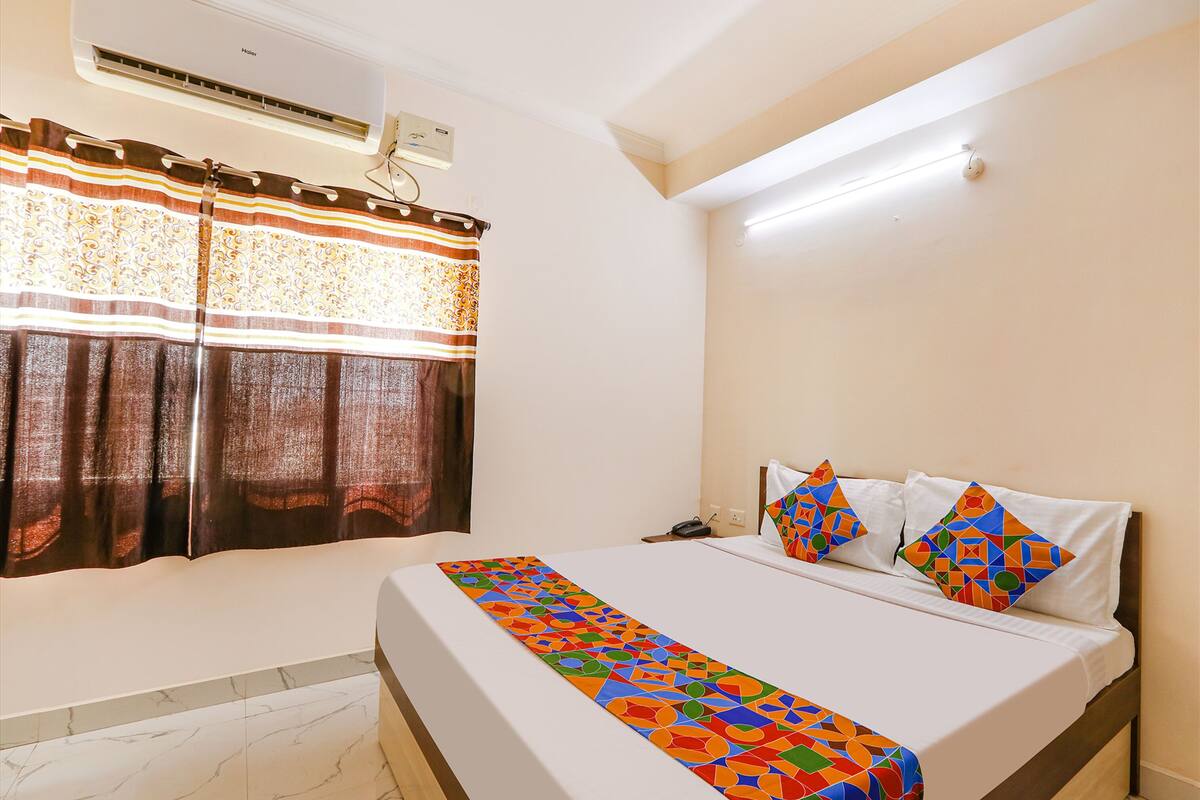 Habitación de hotel con cama, baño y ventana con cortinas.