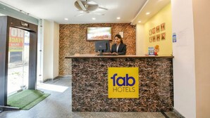 A hotel reception desk with a marble counter, a ceiling fan, and a TV screen. - Via Peaceful Stay Palam (New Delhi)