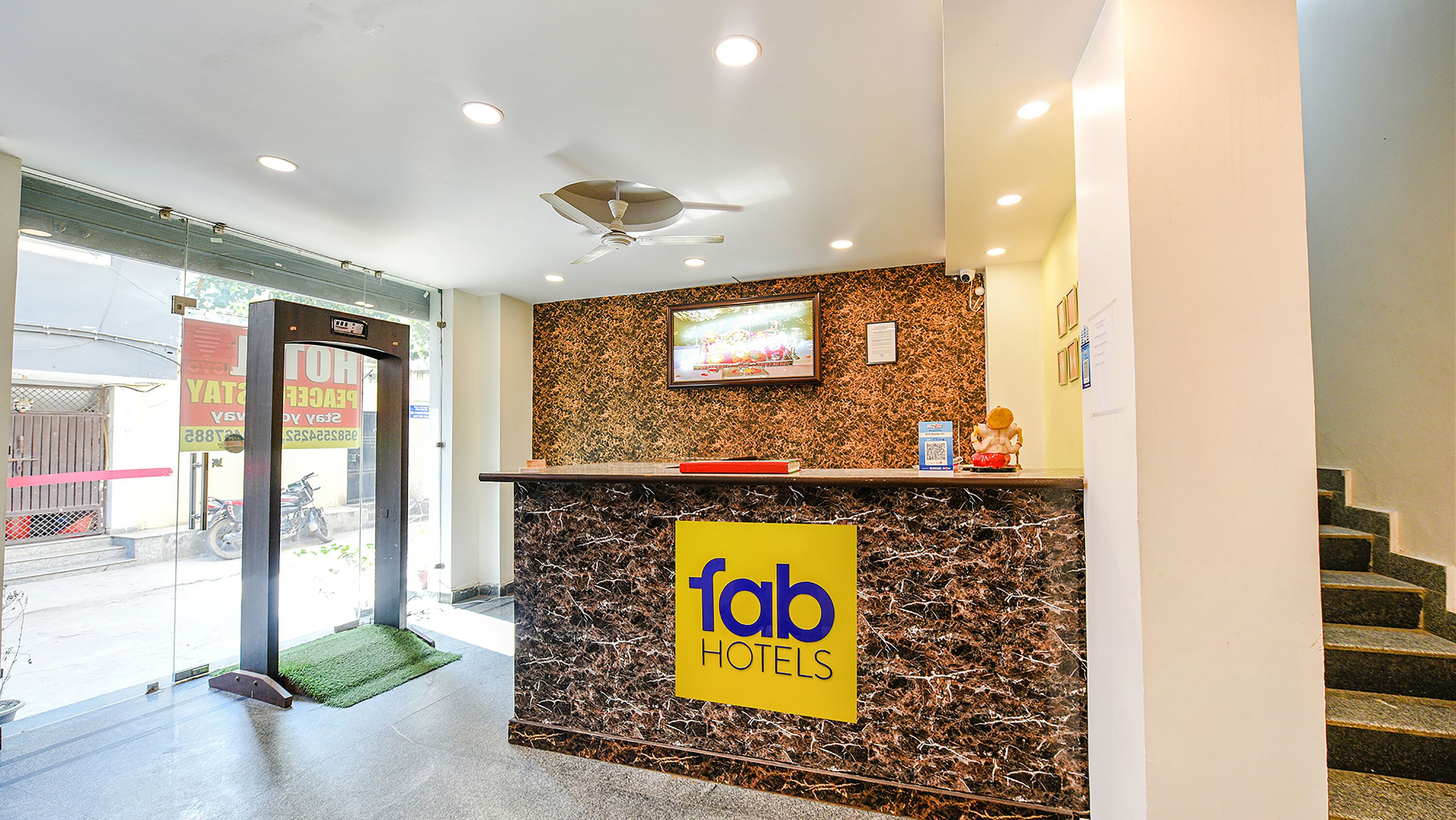 A hotel reception desk with a 'fab hotels' sign, a television, and a staircase to the right.