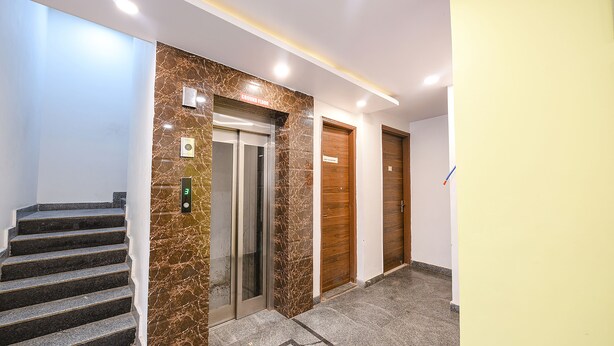 An elevator with a marble wall, a digital display, and a sign above it. - Via Peaceful Stay Palam (New Delhi)
