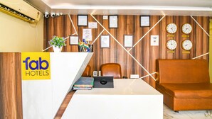 Un área de recepción con un mostrador blanco, un sofá de cuero marrón y varios relojes de pared.