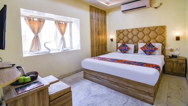 Un dormitorio con cama, escritorio, silla, ventana con cortinas, armario y aire acondicionado.