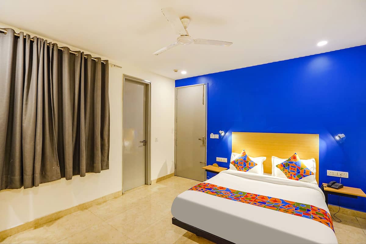 A hotel room with a bed, a ceiling fan, a nightstand, a phone, and a door.