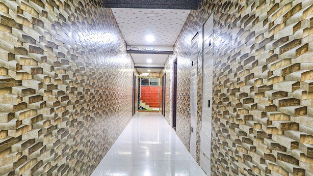 A hallway with a patterned wall and a shiny floor, leading to a room with a red door. - FabHotel The Royal Heritage (Mahabaleshwar)