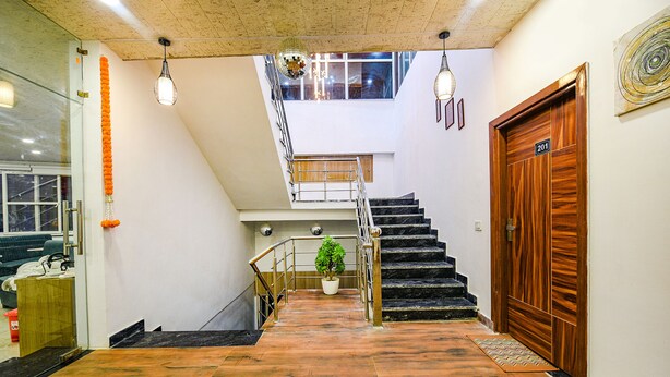 A staircase leading to a second floor with a wooden door marked 201, a potted plant, and a hanging disco ball. - Fabhotel Lake View Ii (Dehradun)