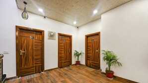 A hallway with three wooden doors labeled 201, 202, and 203, each with a potted plant beside it. - Fabhotel Lake View Ii (Dehradun)