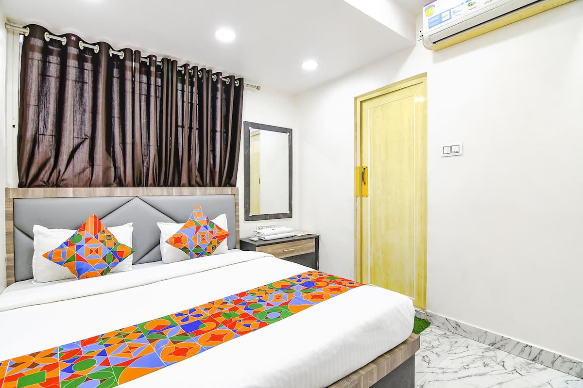 A neatly made bed with a colorful bedspread, a bedside table with a lamp, and a mirror on the wall.
