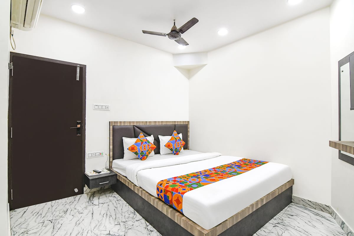 A hotel room with a bed, a nightstand, a ceiling fan, and a door.
