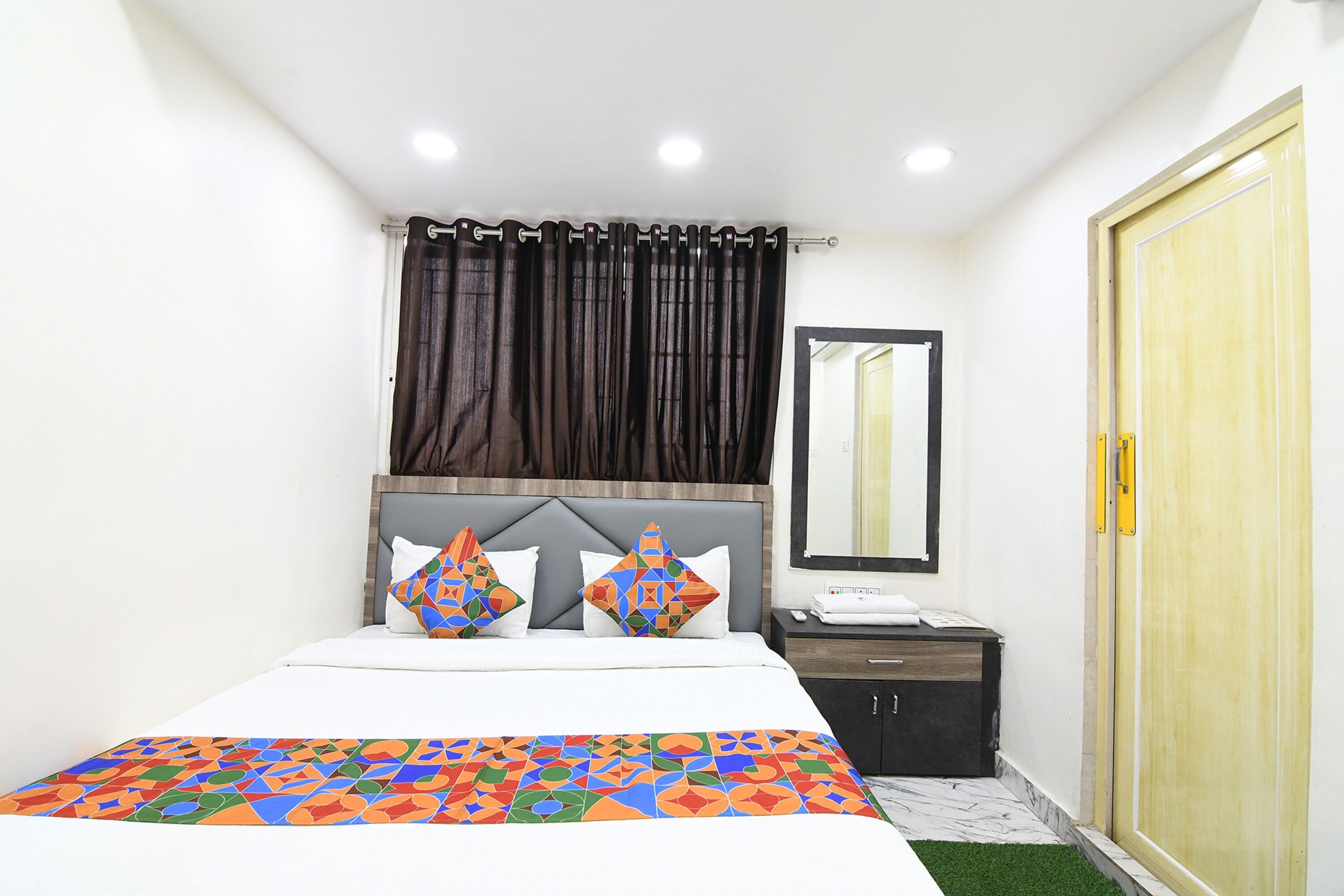 A bedroom with a bed, a nightstand, a mirror, and a wardrobe.