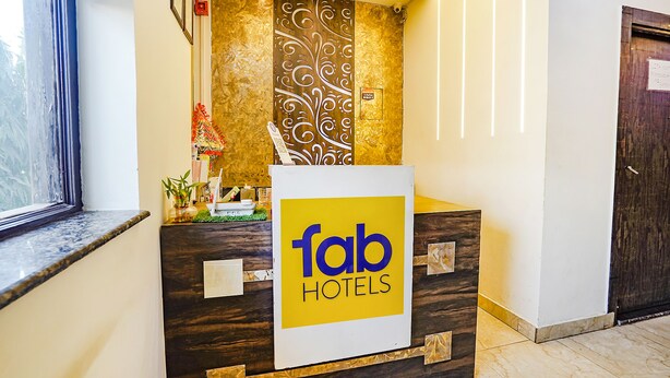 En moderne receptionsdisk på Fab Hotels med et skilt og en dekorativ væg.