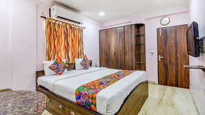 A bedroom with a bed, a TV, a wardrobe, and a bathroom. - Fabexpress Spandan Inn (Barasat)