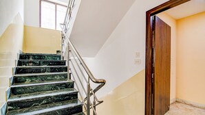 A staircase with marble steps and metal railings, leading to a room with a wooden door and a window. - Fabexpress Spandan Inn (Barasat)