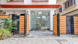 A gated entrance with a tiled pathway leading to a building with a red and white facade. - Fabexpress Spandan Inn (Barasat)