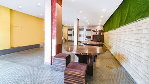Ein modernes Interieur mit einem runden Tisch in der Mitte, Bänken und einer grünen Wand.