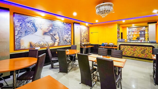 Interior de restaurante com paredes laranja, um candelabro e obras de arte nas paredes.