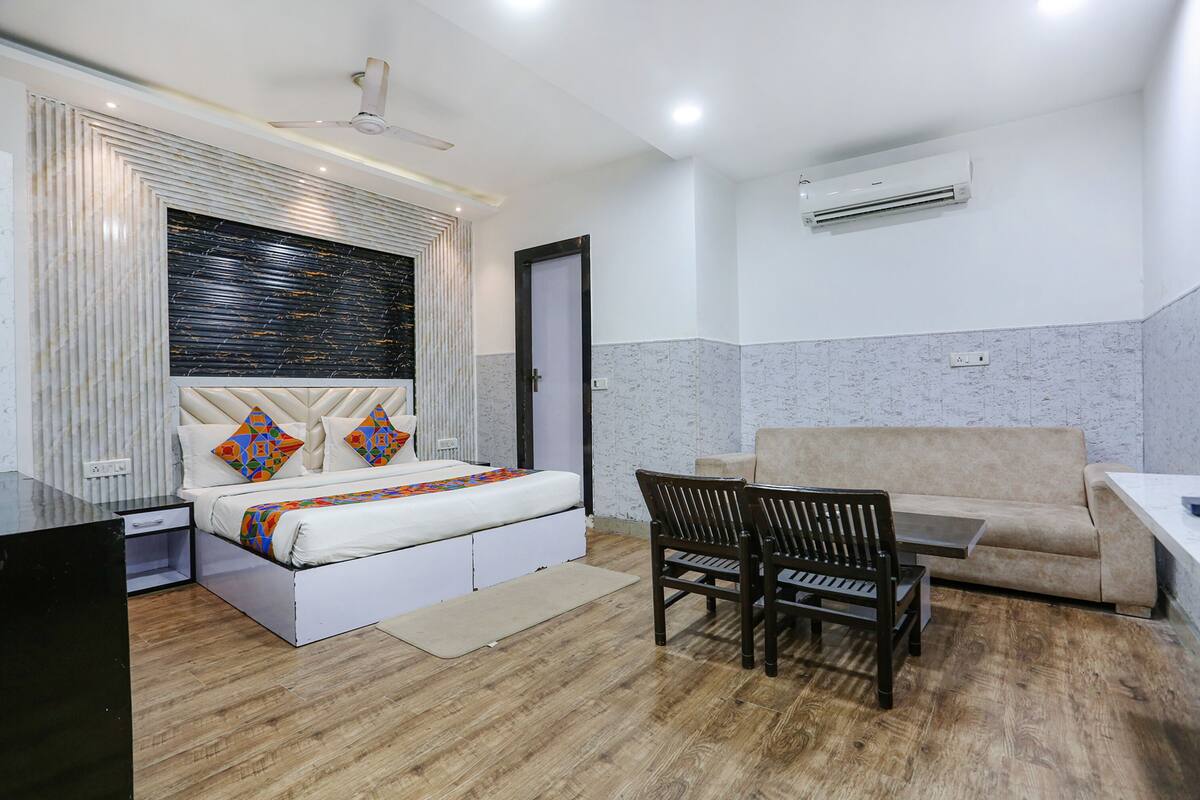 A modern hotel room with a bed, a sofa, a dining table, and a chair.