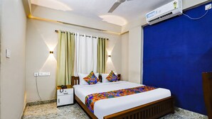 Un dormitorio con cama, mesita de noche, aire acondicionado de pared y una puerta azul.