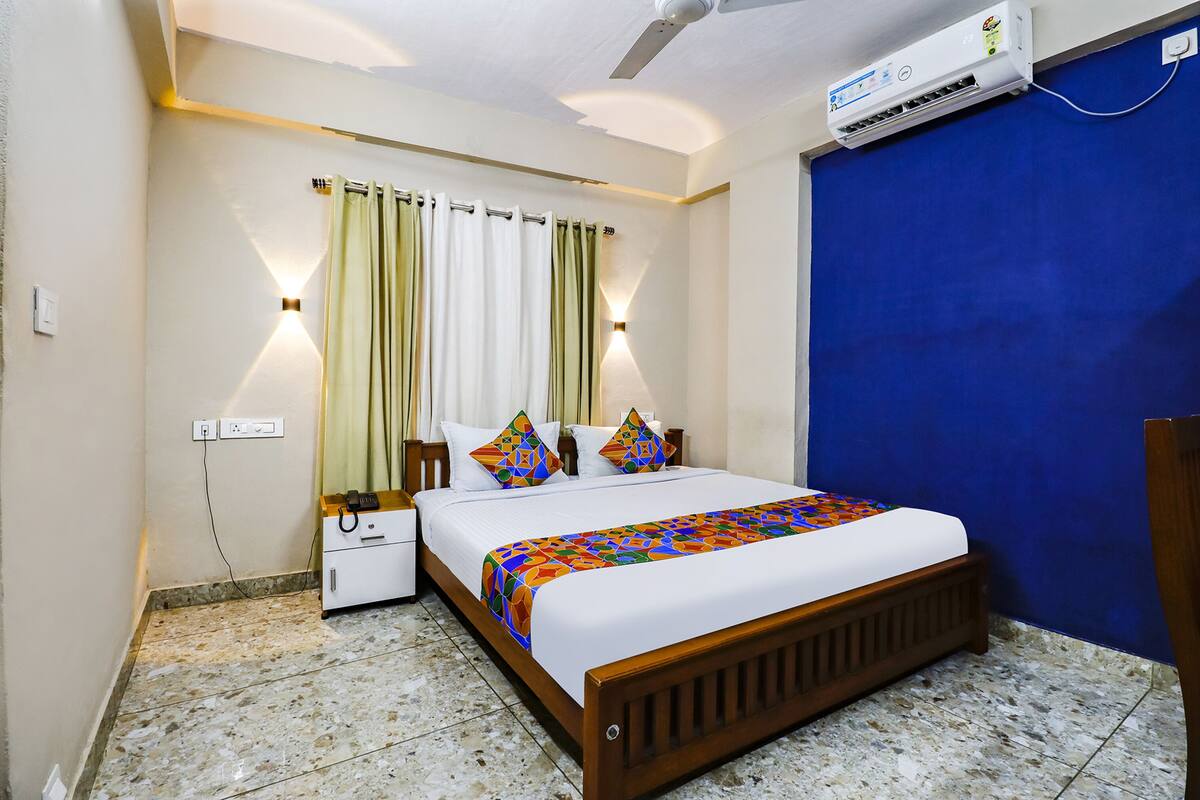 A bedroom with a bed, nightstand, wall-mounted air conditioner, and a blue door.