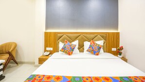 A hotel room with a bed, a nightstand, a chair, and a wall-mounted air conditioner. - FabHotel Hari Kunj 900 m from Kashi Vishwanath Temple (Varanasi)