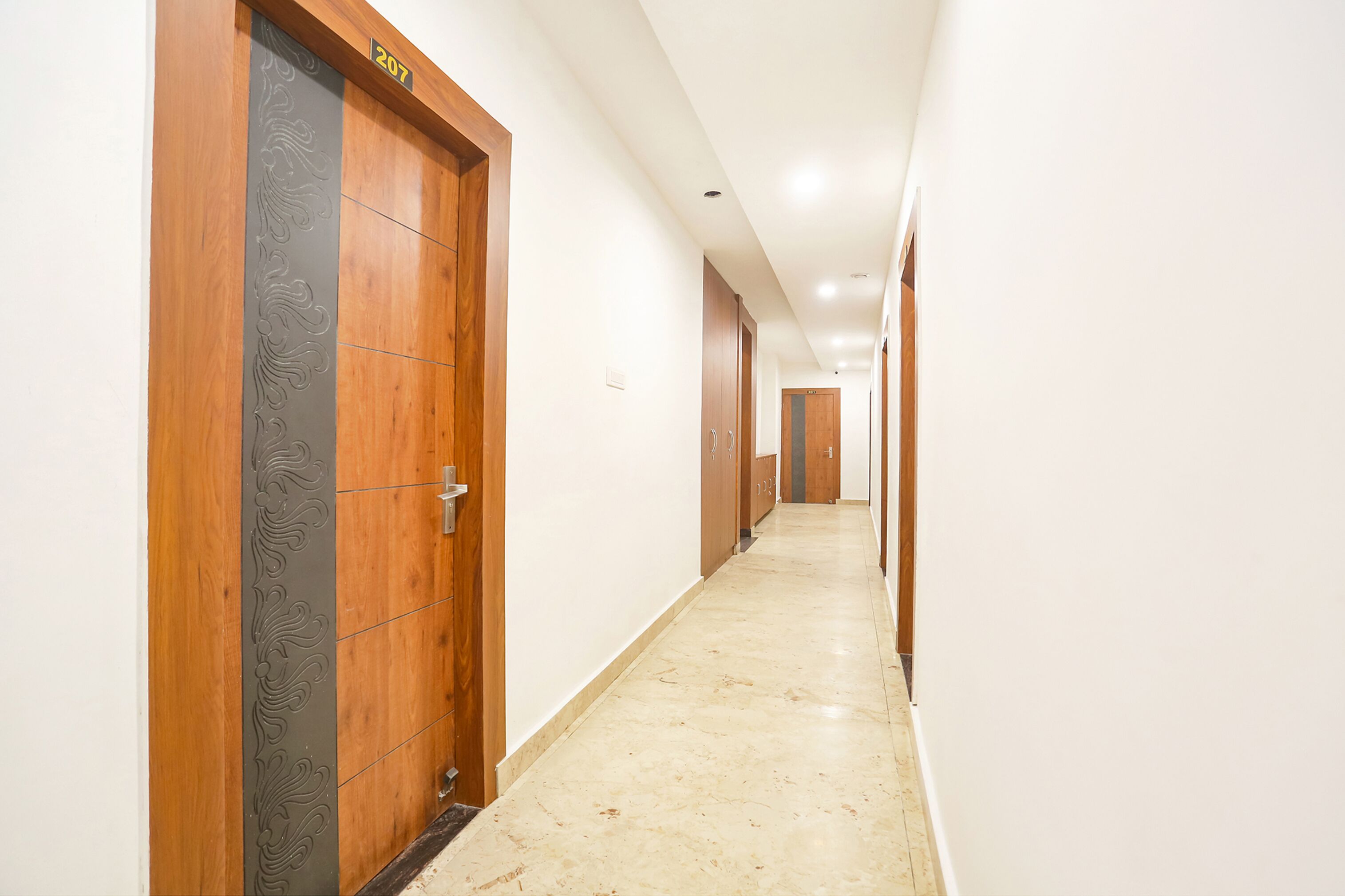 Um corredor comprido e estreito com portas de madeira e chão de azulejos.
