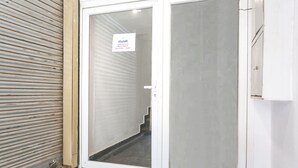 A closed sliding glass door with a 'Welcome' sign, a metal shutter door to the left, and a white wall. - FabHotel Hari Kunj 900 m from Kashi Vishwanath Temple (Varanasi)