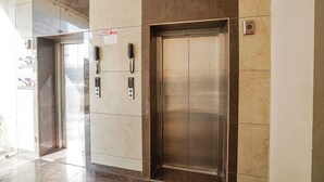 An elevator with a phone and a control panel, surrounded by marble walls. - Fabhotel Hk Villa (Vadodara)