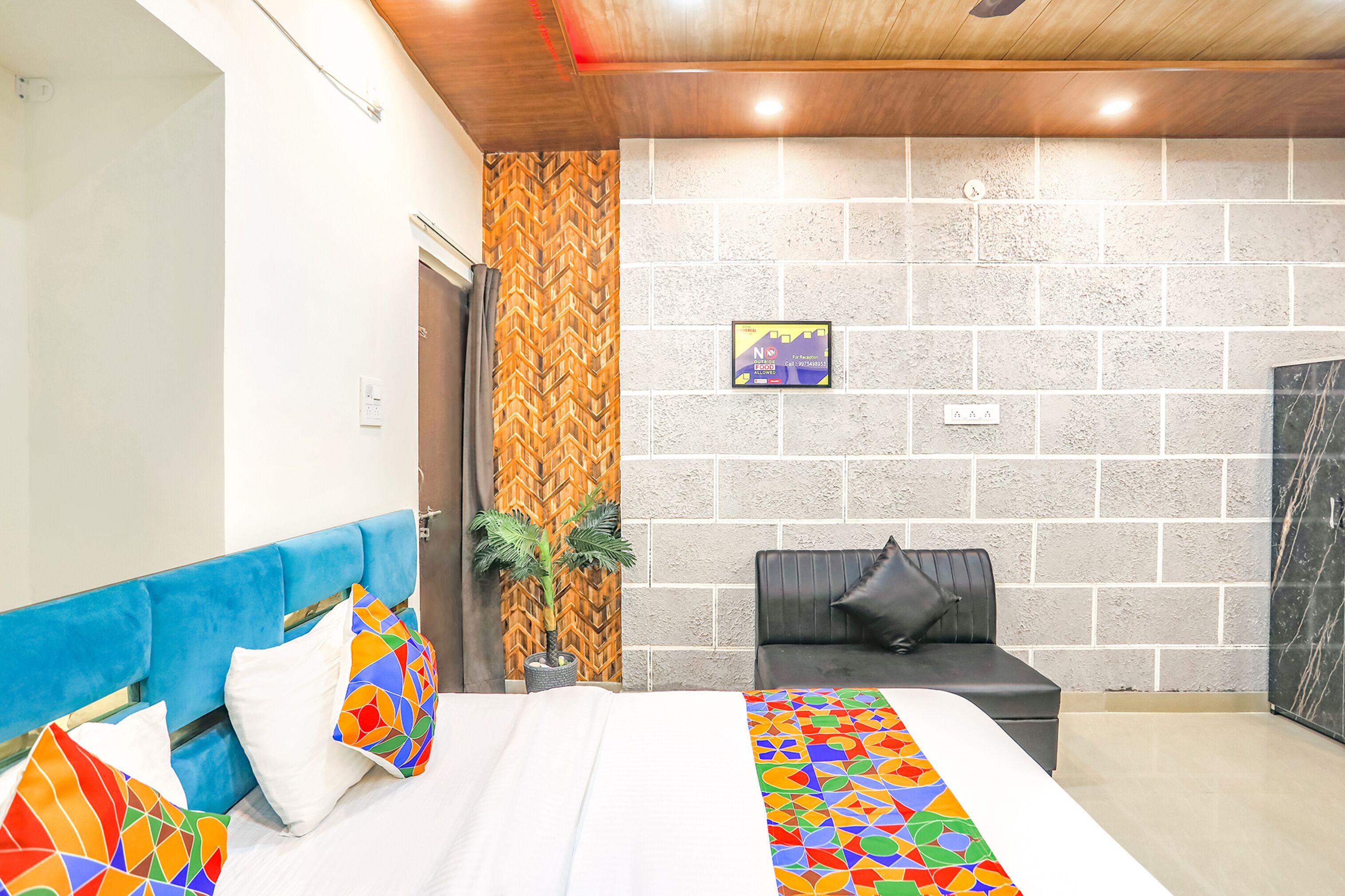 Una habitación de hotel con una cama, un sofá, una planta en maceta y un reloj de pared.