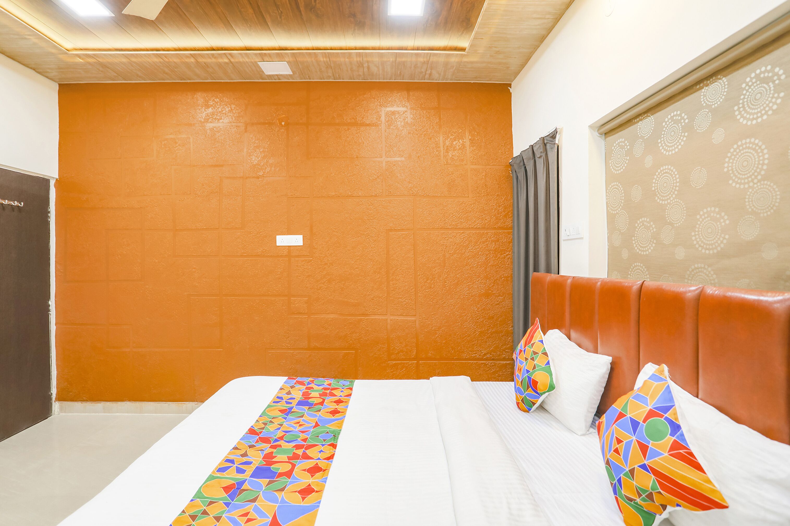 A hotel room with a large bed, a headboard, and a wall with a geometric pattern.